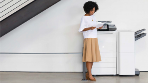 Woman looking at printouts in front of a large printer